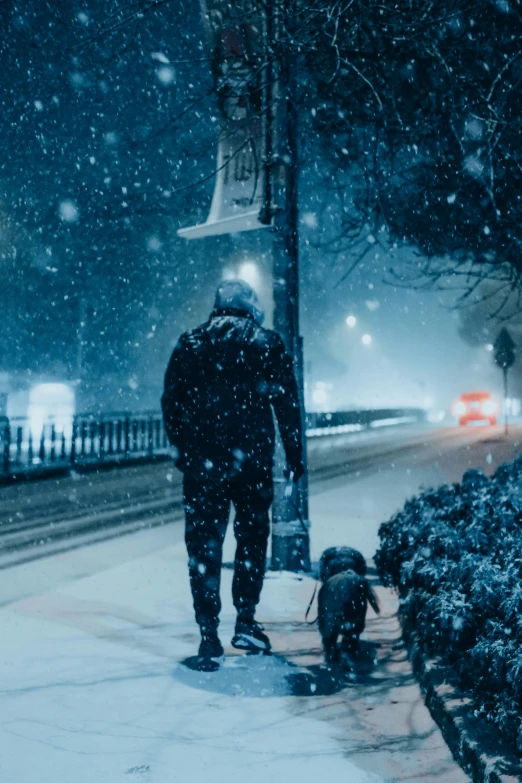 man walking dog in snowy winter scene in urban area