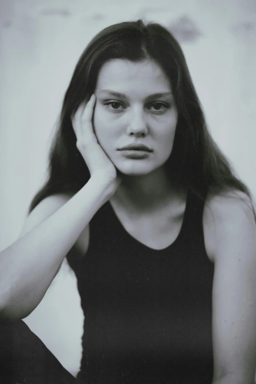 a woman with long hair holds her hand up to her face