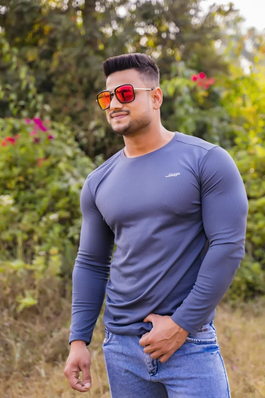 the young man is wearing sunglasses and standing by the grass