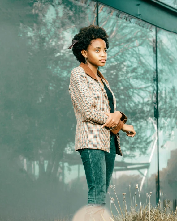 a woman standing by some plants and a wall