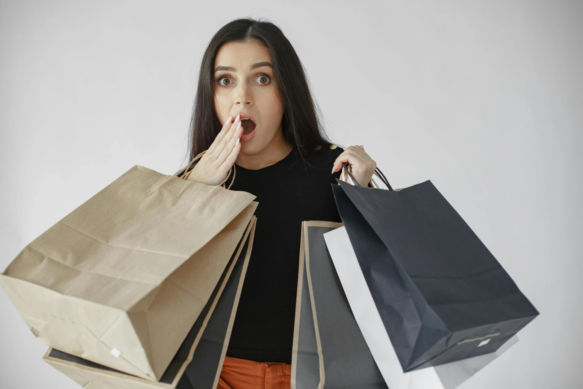 a girl is shocked as she holds shopping bags