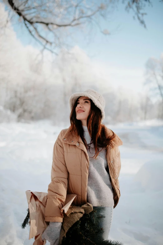 a woman walking across snow covered ground with a hat on