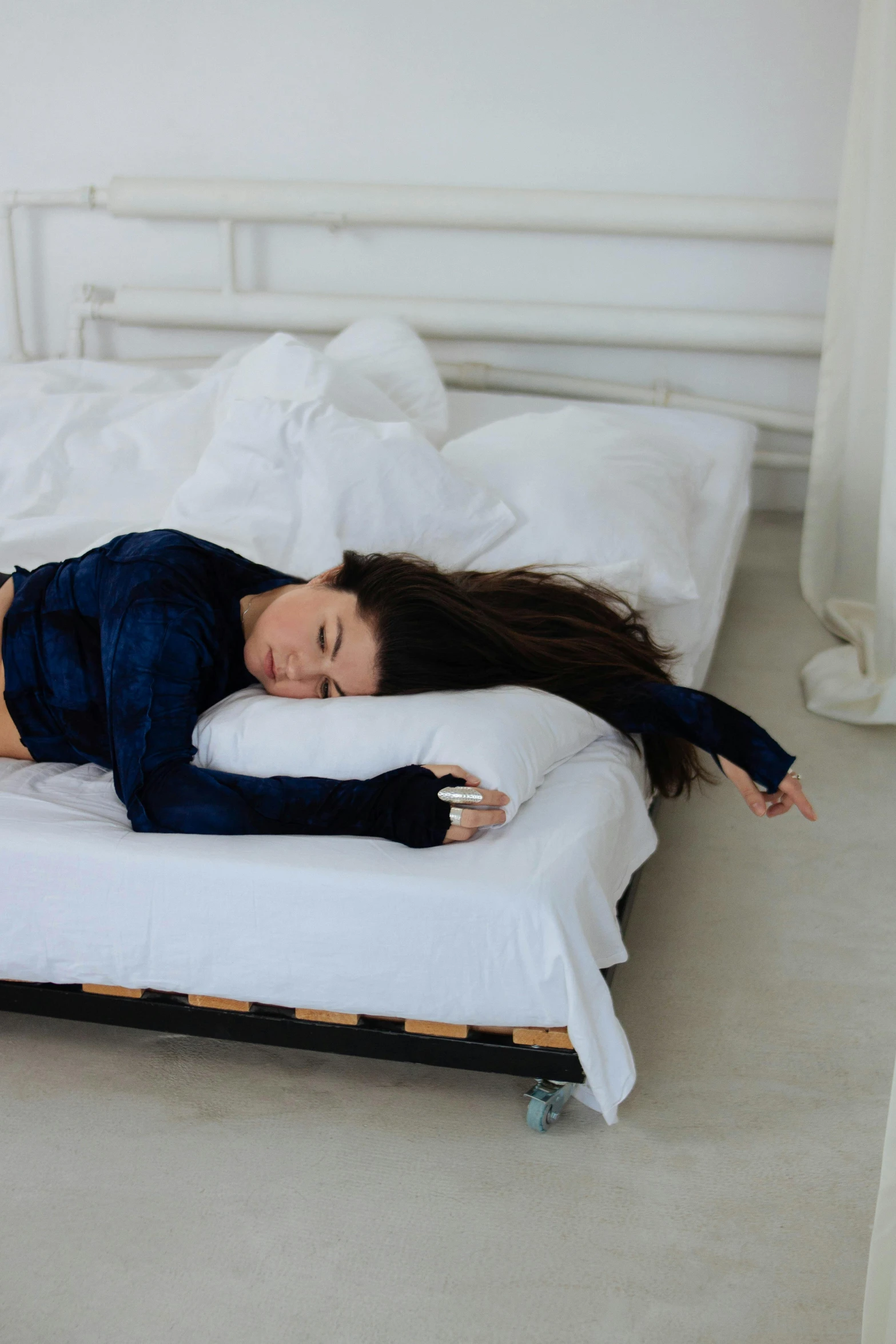 a woman in dark shirt laying on a bed