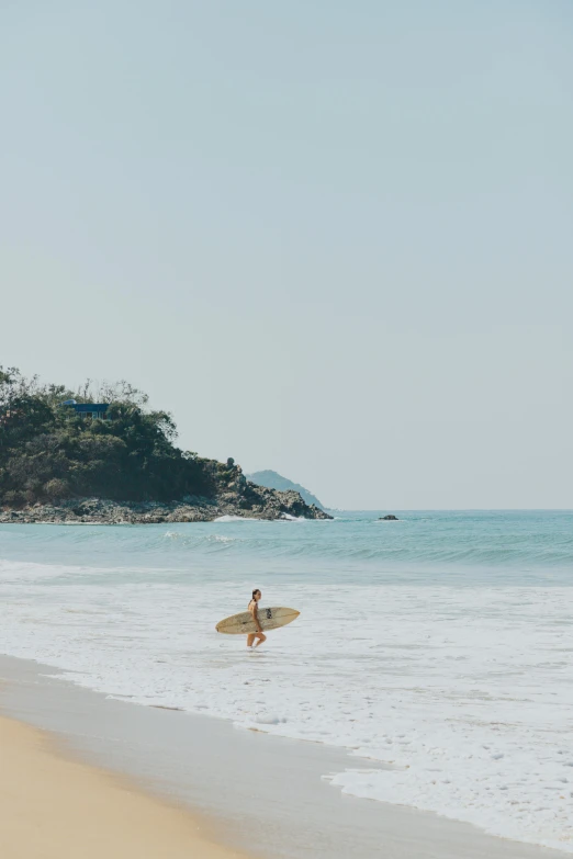a person walking into the ocean with a surfboard