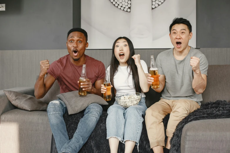 three men and two women holding beers sitting on a sofa