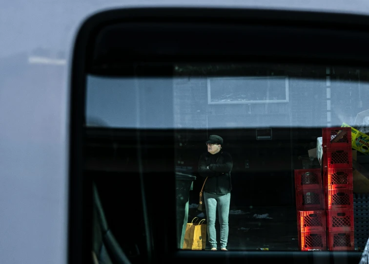 a man holds his luggage as he looks out the back of a vehicle window