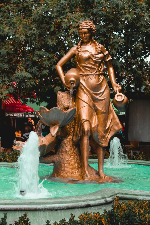 a statue with a hat on her head near a fountain