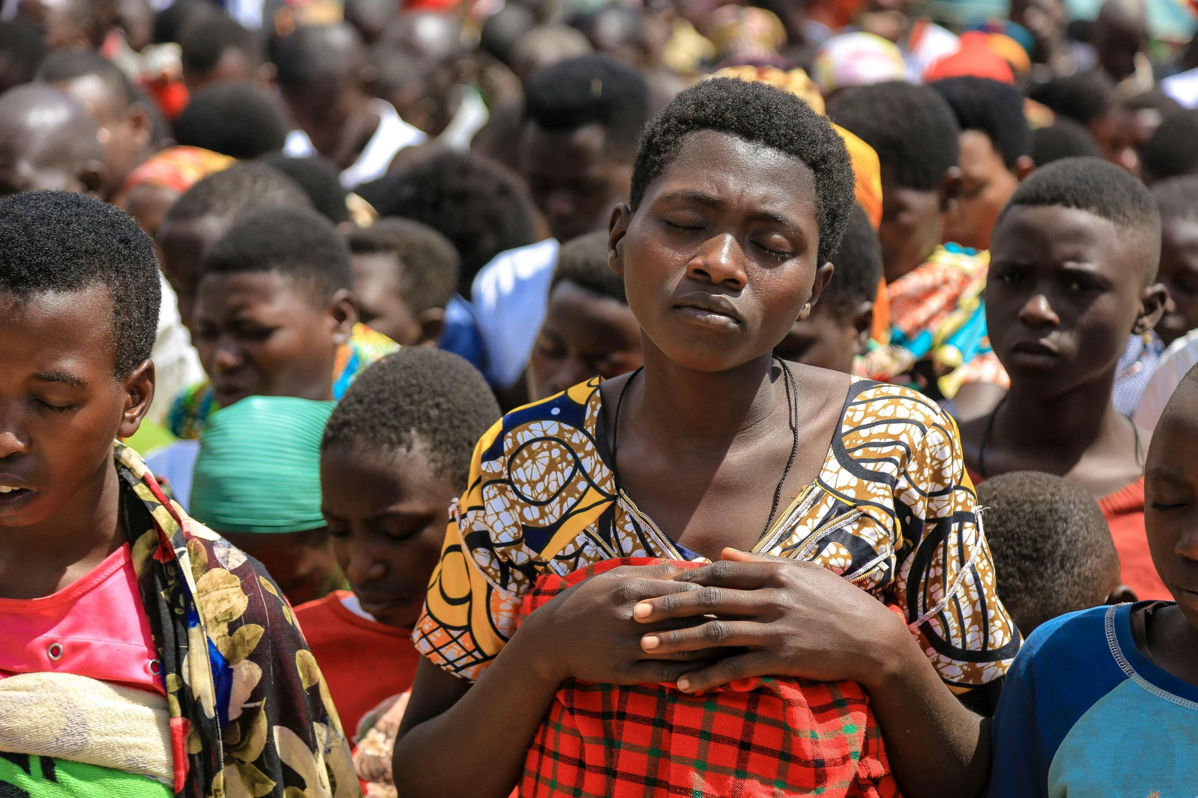 woman in africa holding a cell phone and sitting amongst people