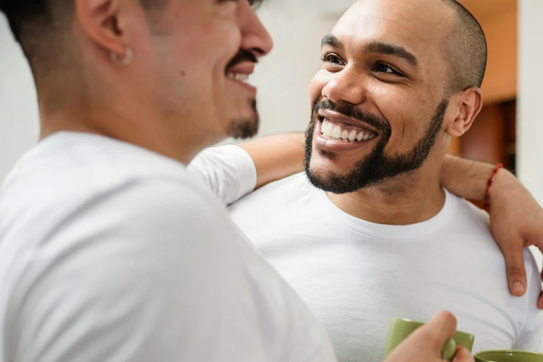 two men smile while holding one another