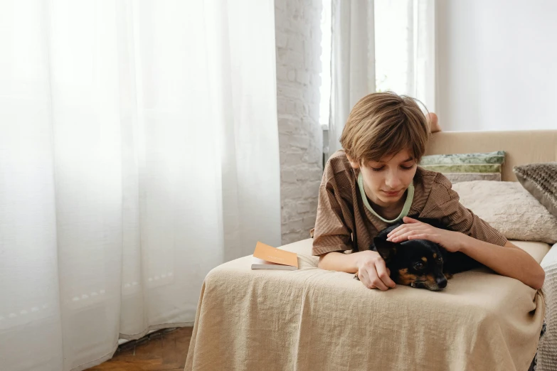 a girl in a brown jacket laying on a couch petting her dog