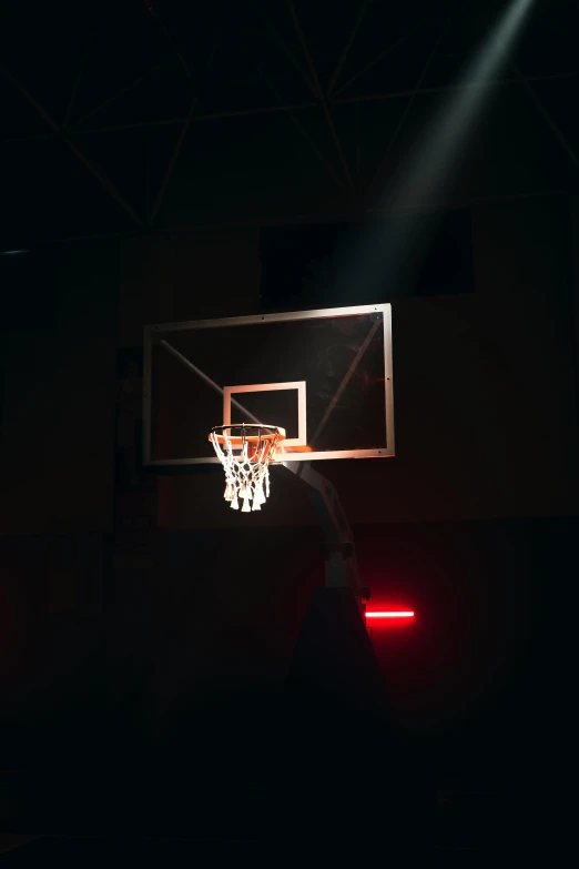 a basketball hoop in a dark building lit by spotlight