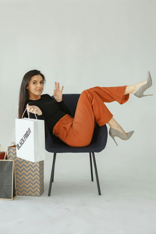a girl sitting on a blue chair with a white bag and some shopping bags