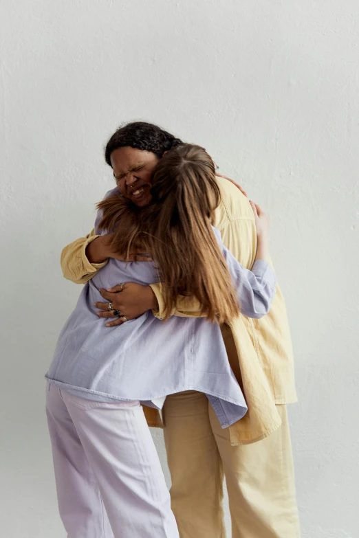 two women hugging each other on the side of a wall