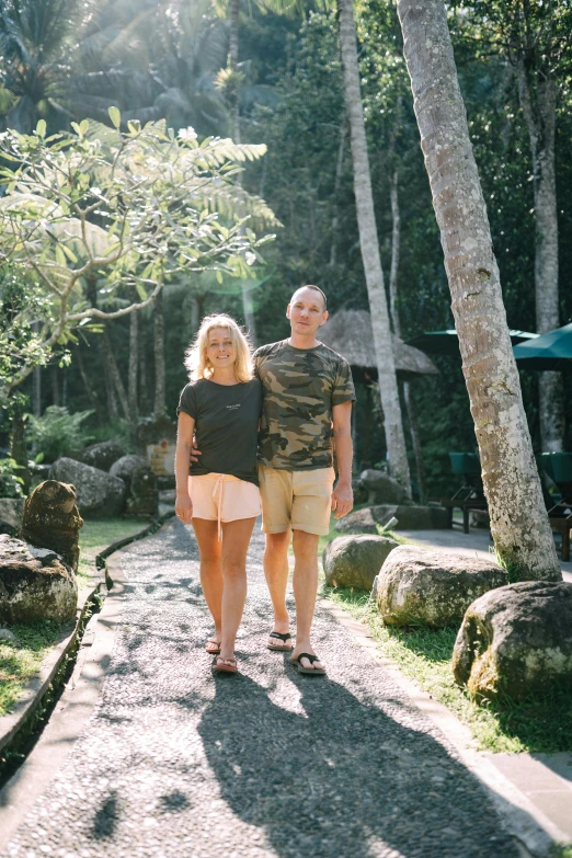 the couple is walking down the path through the forest