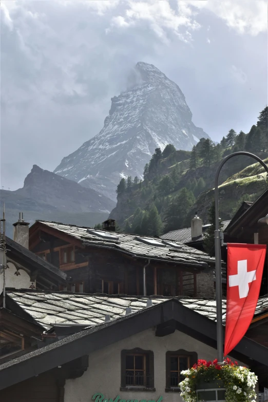 a flag on top of a street pole in front of a building with a mountain behind it