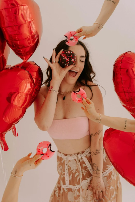 a woman eating a donut surrounded by balloons and hearts