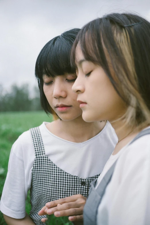 two woman sitting together in a grassy field