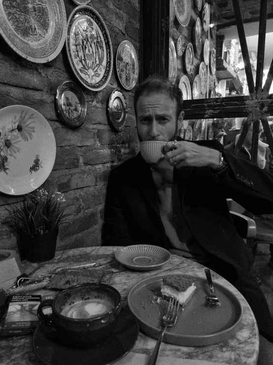 man in black and white eating with a cup