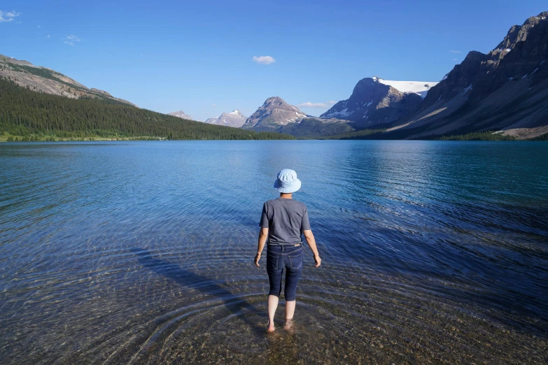 a young man stands in the shallow water of a lake