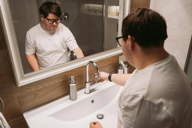 a man in a white t - shirt is at the sink