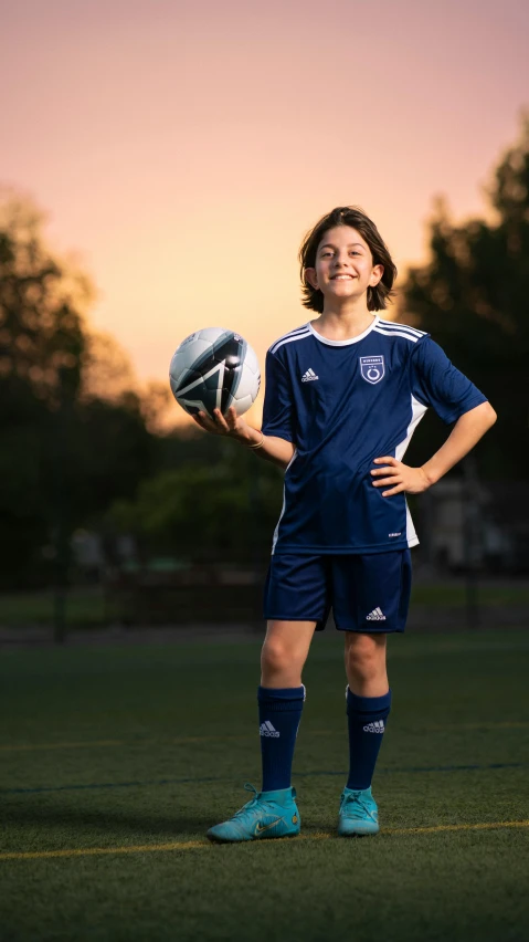 a young person stands holding a soccer ball