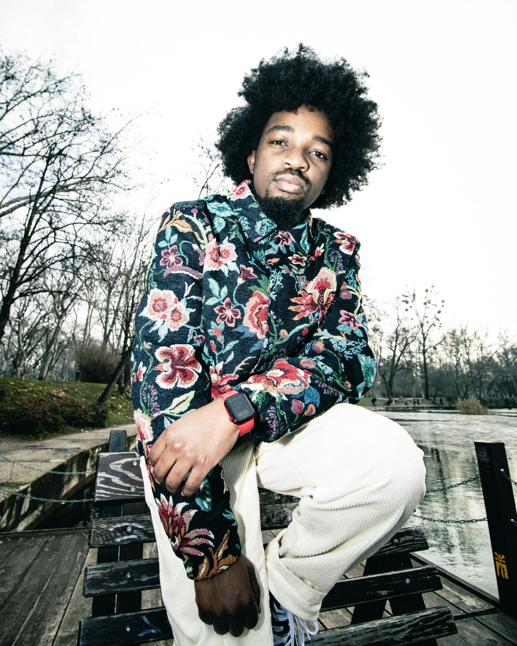 a man wearing floral print jacket sitting on a bench
