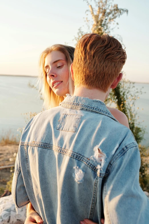 a girl that is hugging another person next to a water