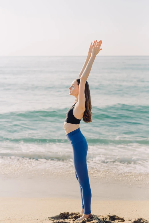 a pregnant woman practices yoga on the beach