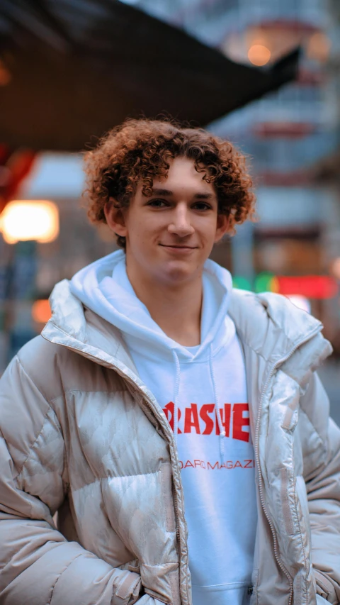 a young man with a large, curly hair standing in front of a building