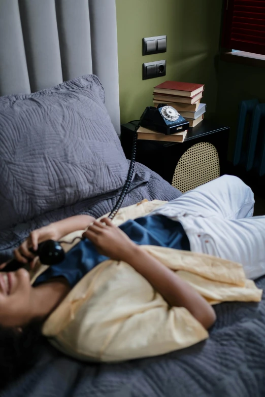 a young woman laying in bed with an alarm clock