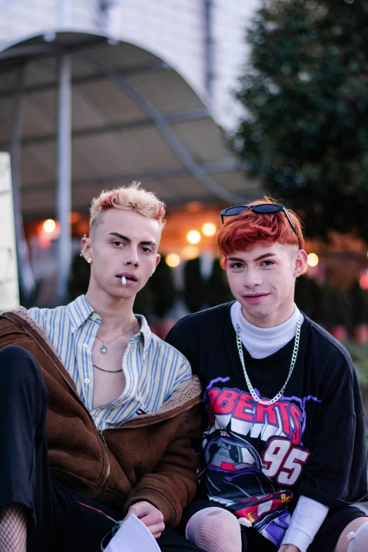 two young men sitting on the ground with their tongues sticking out