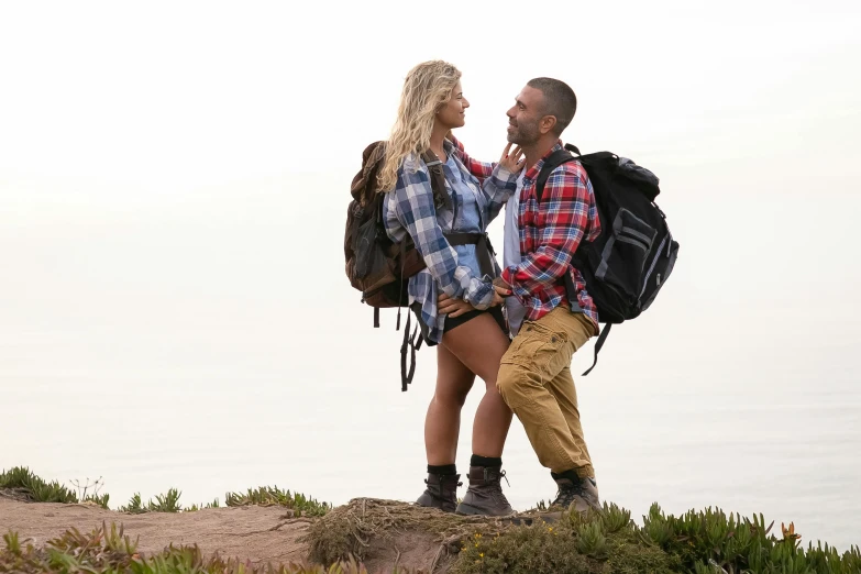 a man and woman are standing on a rocky hill looking into each other's eyes