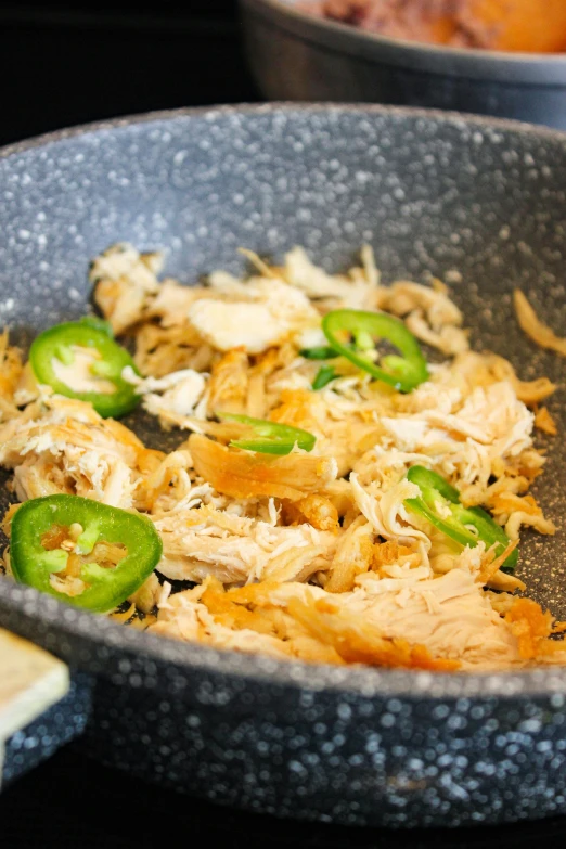 chicken and peppers being cooked in a pan