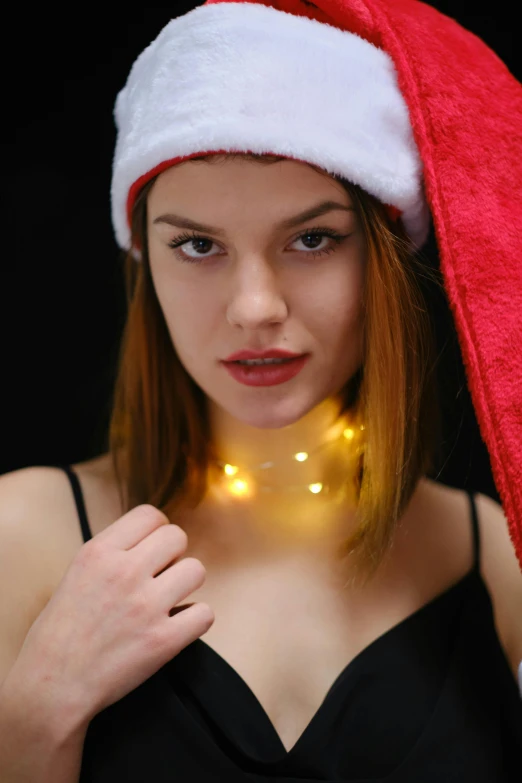 a woman in a santa hat is wearing a yellow light up necklace