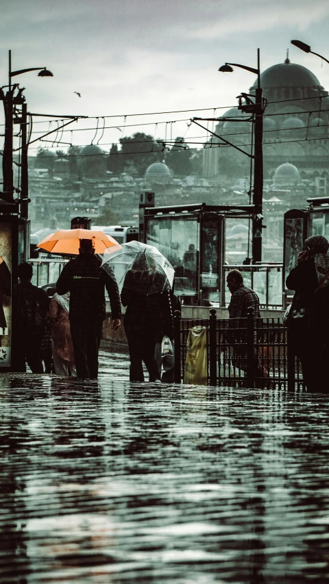 a group of people walking on the street in rain with umbrellas