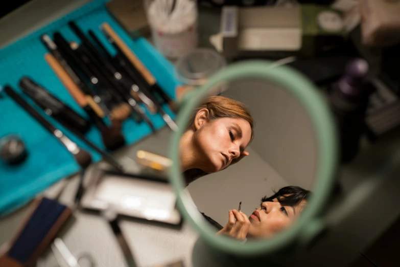 two women looking into a mirror with their reflection in it