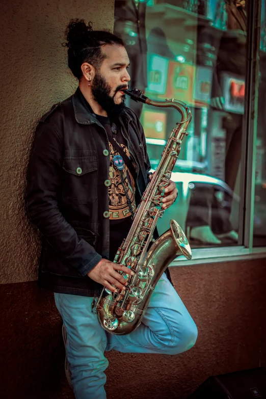 a man leaning on a wall with his saxophone in his hand