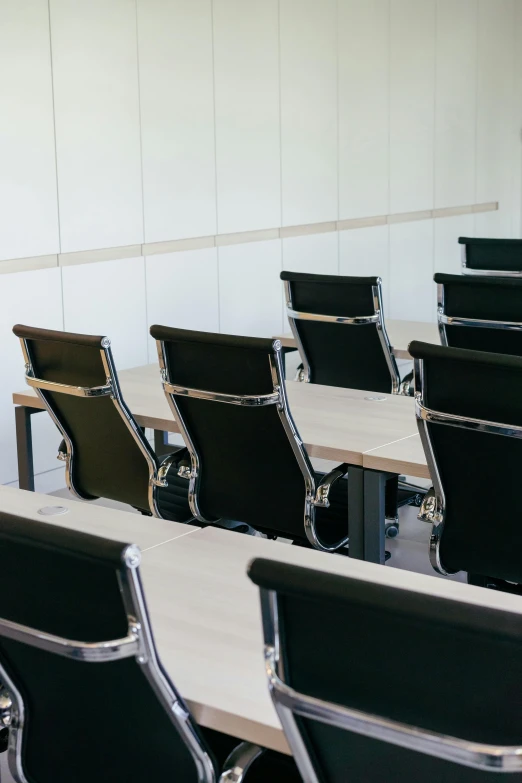 rows of black seats and desks are arranged in front of the white wall