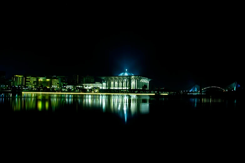 a nighttime scene with a large building and a lake