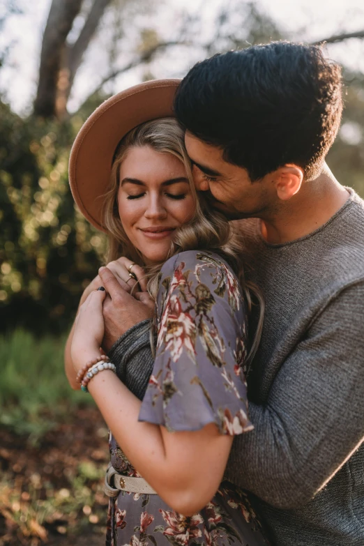 a man and woman hug each other as they are standing in a wooded area