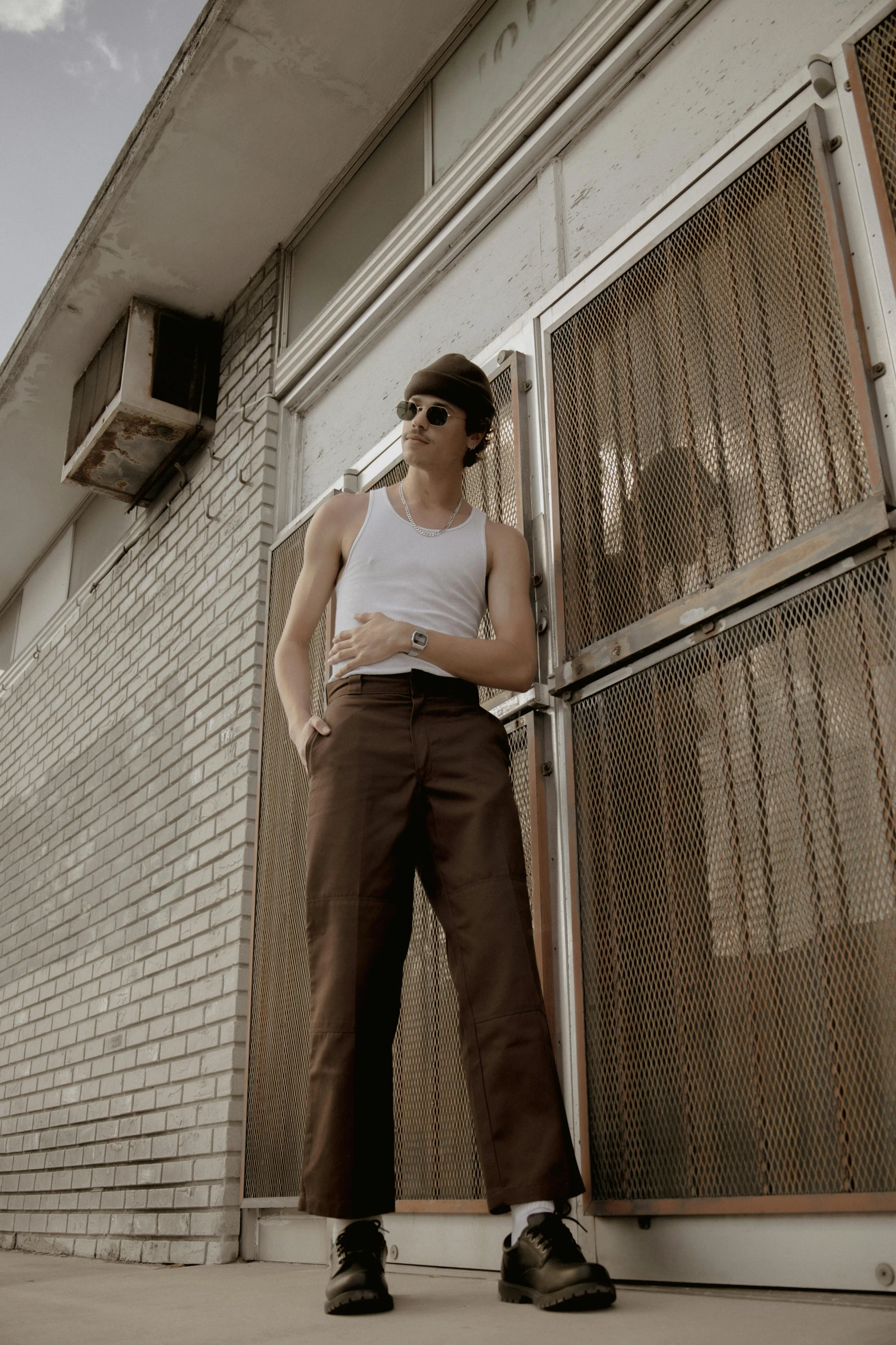 a man leaning against a building wearing sunglasses