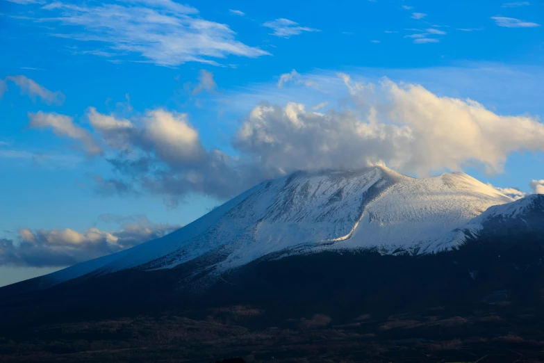 snow covered mountains under a blue sky filled with clouds