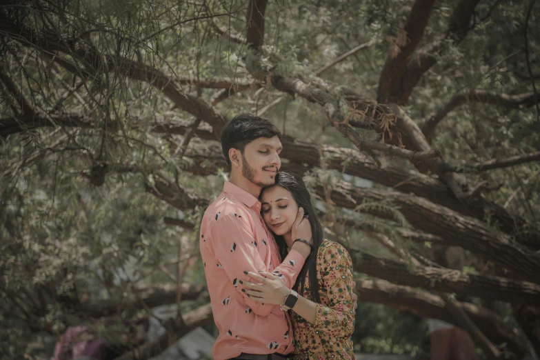 a couple emce under a tree in an outdoor setting