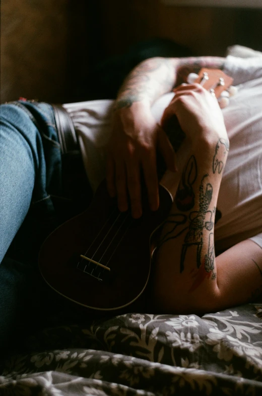 a person with tattoos on their arms sitting and holding an instrument