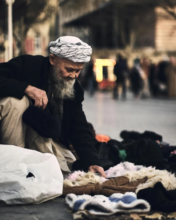 an old man is sitting down by his belongings