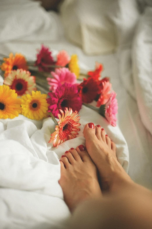 a person's foot next to flowers and a sheet