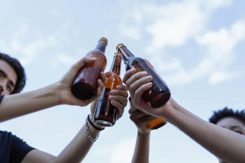 a group of people holding up brown bottles