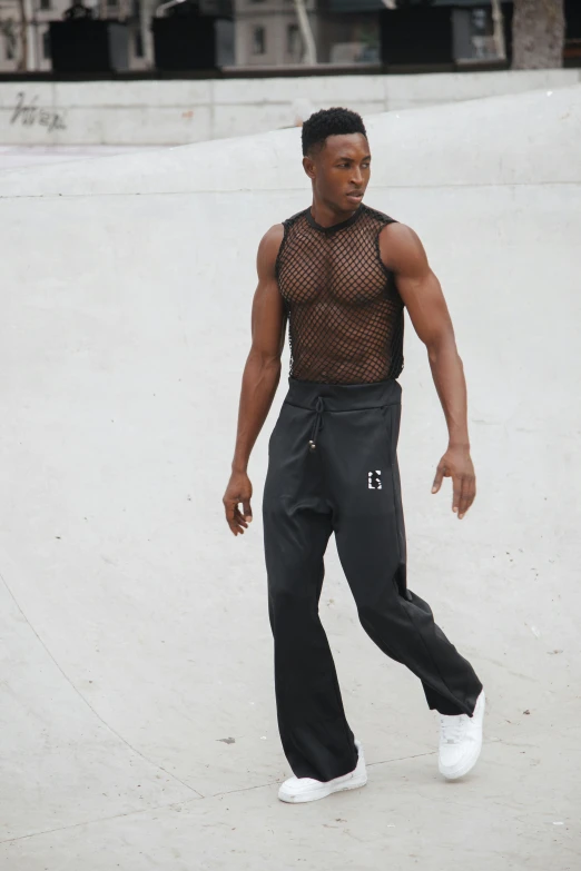 a man wearing white shoes and a mesh top with  on