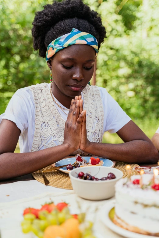 a woman in white shirt sitting at a table with cake