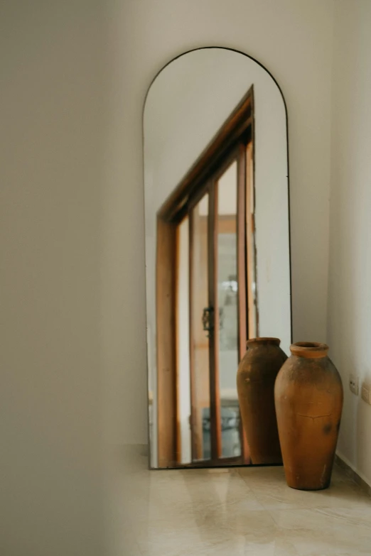 a couple of brown vases sitting in front of a mirror